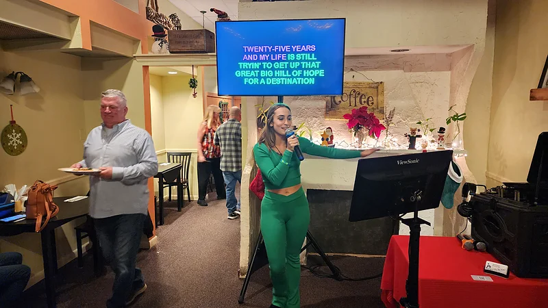 A singer following the on-screen lyrics during a hosted karaoke night